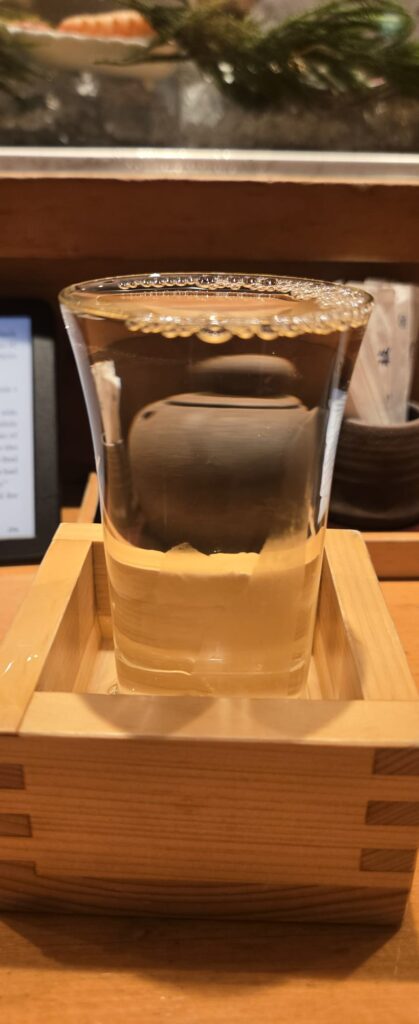 Glass of Japanese sake resting in a wooden masu box