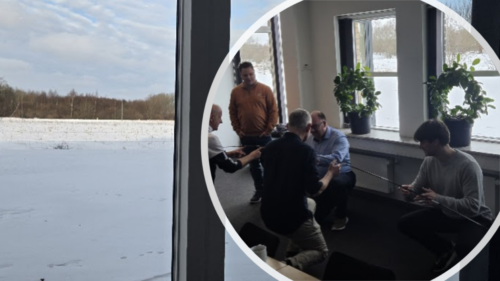 Group of colleagues indoors collaborating with strings, seen through a window overlooking a snowy landscape.